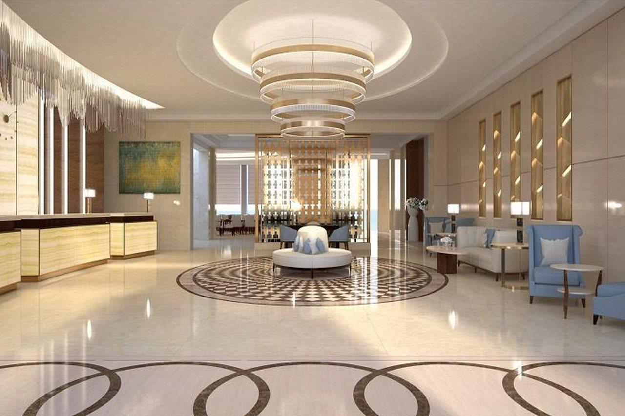 Grand Swiss-Belhotel Waterfront Seef Sanabis Exterior photo The photo shows a modern and elegant lobby area. It features a high ceiling adorned with stylish light fixtures. In the center, there is a round seating arrangement with a decorative piece. The floor has a sophisticated pattern, likely made of marble