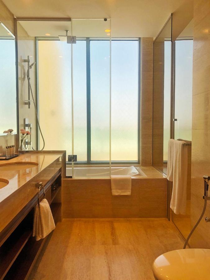 Grand Swiss-Belhotel Waterfront Seef Sanabis Exterior photo The photo features a modern bathroom with a clean and stylish design. It includes a double sink vanity with a wooden countertop and a large mirror. A shower area is visible with a glass wall, allowing for an open feel. There is a bathtub next to a wi