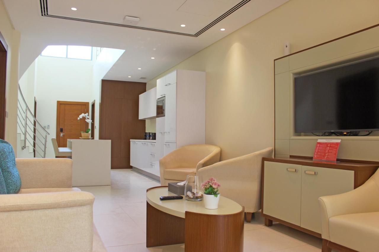 Grand Swiss-Belhotel Waterfront Seef Sanabis Exterior photo The photo displays a modern and stylish interior space, likely a living room or lounge area. The design features light-colored walls and furnishings, creating a bright and airy atmosphere. 

In the room, there are two armchairs and a small round coff